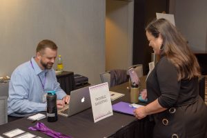 Friendly guest interaction at event registration table for troubleshooting assistance