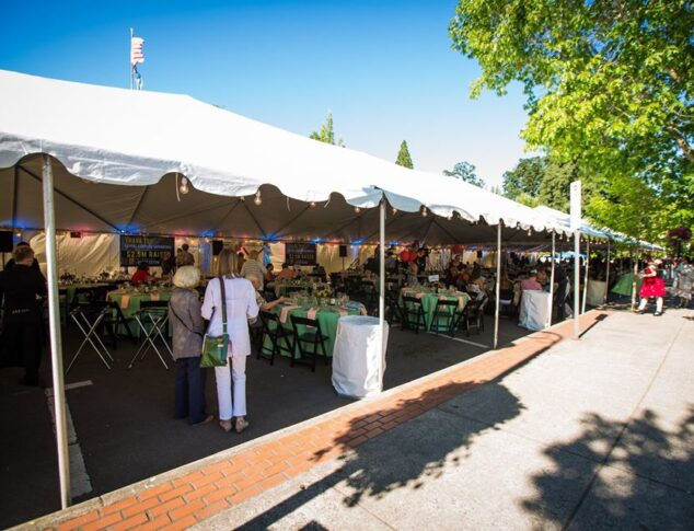Tented venue space with pink and green tables and guests underneath on a sunny day in Forest Grove