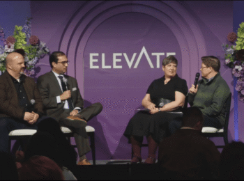 Four speakers seated on a stage with microphones against a purple backdrop with the word Elevate printed in large letters